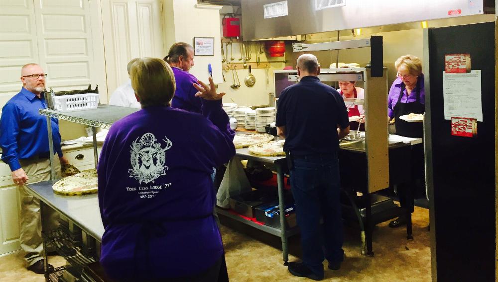 Officers and volunteers preparing to serve dinner to the Veterans and their guest.