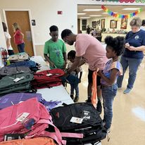 Dad helping this 3 children pick out backpacks with Pam