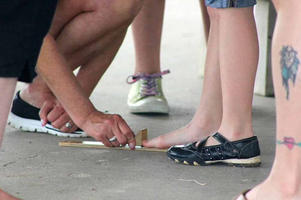 A volunteer measures children's feet to ensure a perfect fit for their new pair of shoes.