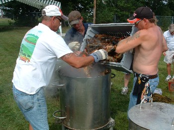 Members's field day committee chairman Denny LeClair and two helpers drop the first load of lobsters into the pot. 